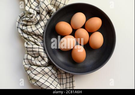 Uova di pollo marroni in ciotola nera Foto Stock