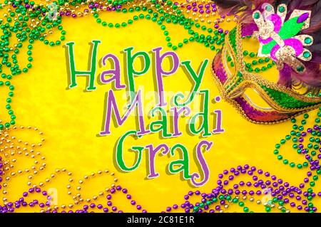 Happy Mardi Gras e Fat Martedì carnevale tema con primo piano su una maschera viso pieno di colore, piume e texture e oro, verde e viola Foto Stock