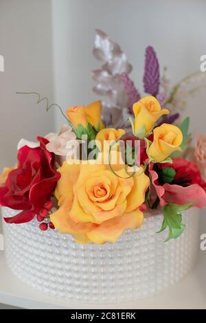 Elegante decorazione floreale per una torta nuziale, coperta di glassa reale e perle di zucchero posizionate simmetricamente, con rose in pasta alimentare di zucchero Foto Stock