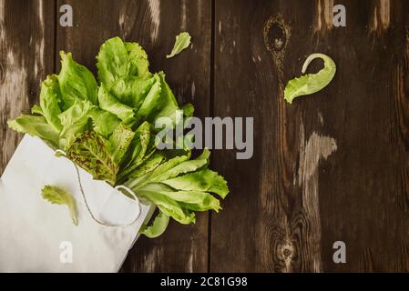 Fresco Lettuce Lleeson in una borsa di carta un tavolo di legno scuro. Insalata di Batavia Foto Stock