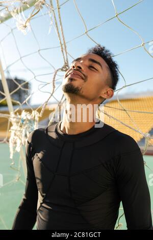 Ritratto di bel sportivo afroamericano sognato in piedi in gol calcistico allo stadio Foto Stock