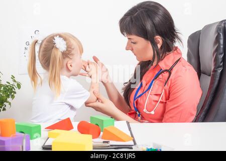 Un medico allergista esamina la mano di un bambino con rossore e un'eruzione cutanea sulla pelle. Il concetto di dermatite e orticaria in un bambino, sfondo, ipopio Foto Stock