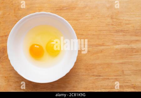 Due uova di pollo, fatte in casa e in fabbrica, sono spezzate in un piatto di vetro. Concetto di differenza di uova naturali fatte in casa da negozio-comprato, biologico Foto Stock