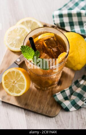 Bevanda a base di tè freddo con limone in vetro e ghiaccio su tavolo di legno bianco Foto Stock