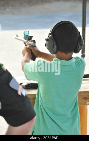 Un giovane afroamericano prende un obiettivo attento con un'arma da fuoco. Foto Stock