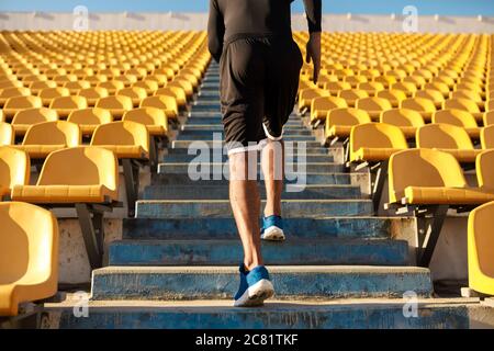 Primo piano vista posteriore di sportivi che corrono tra i posti vuoti dello stadio Foto Stock