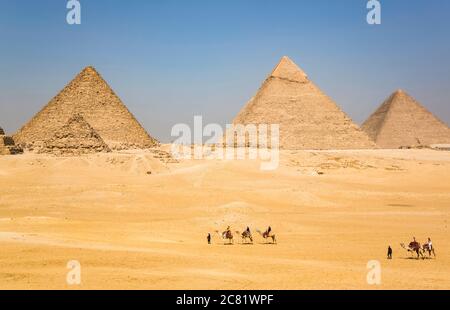 I turisti che cavalcano i cammelli, il complesso della Piramide di Giza, Sito Patrimonio dell'Umanità dell'UNESCO; Giza, Egitto Foto Stock