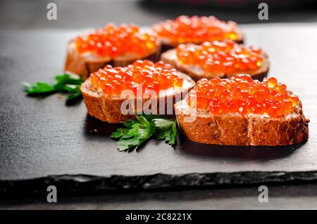 Caviale rosso sul pane su sfondo di ardesia. Foto Stock