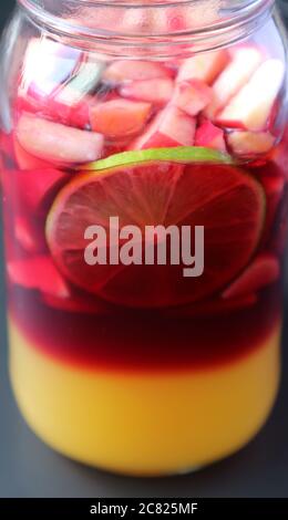 Colore vivace della sangria di vino rosso fatta in casa in una bottiglia di erba prima di mescolare Foto Stock