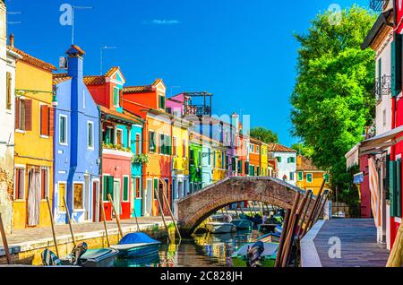 Case colorate dell'isola di Burano. Edifici multicolore su argine di fondamenta, stretto canale d'acqua con barche da pesca e ponte di pietra, provincia di Venezia, Regione Veneto, Italia. Burano cartolina Foto Stock