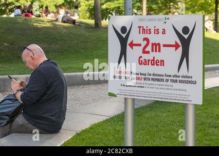 Londra, Regno Unito. 20 luglio 2020. Un cartello che dichiara i Giardini Jubilee sulla South Bank un 'Giardino da 2 m' serve come promemoria per le persone che godono del caldo tempo. I cartelli per tenere a 2 metri di spazio sociale di distanza si possono trovare in molti luoghi pubblici intorno a Londra, ma le regole non sono sempre seguite, come molte persone godono il relax di blocco e socializzare nel caldo tempo. Credit: Imageplotter/Alamy Live News Foto Stock