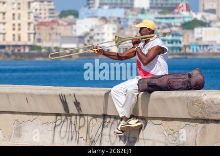 Un musicista di strada suona il trombone presso il famoso muro di Malecon sul mare a l'Avana Foto Stock