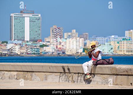 Un musicista di strada suona il trombone presso il famoso muro di Malecon sul mare a l'Avana Foto Stock