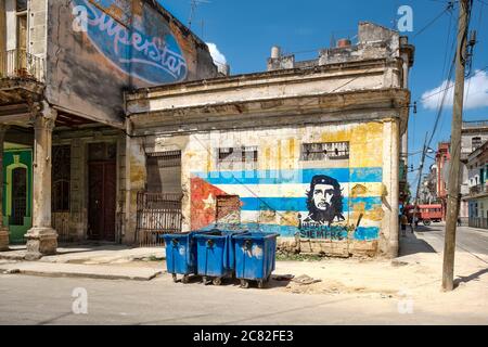 Decadendo vecchi edifici a l'Avana con un'immagine di che Guevara e una bandiera cubana dipinta su un muro Foto Stock