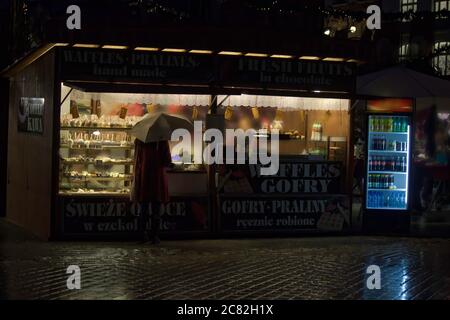 Cracovia, Polonia - 22 dicembre 2014: Vista posteriore di una donna in giacca invernale che tiene un ombrello di fronte al negozio di waffle durante il Natale anche in città ce Foto Stock