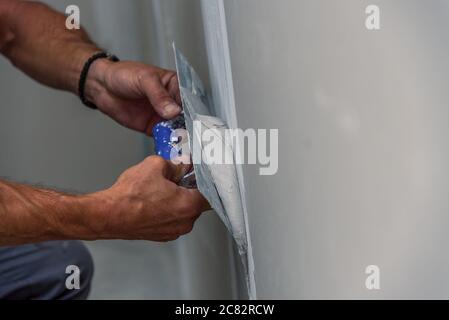 Vecchio lavoratore manuale con muro di intonacatura rinnovando gli strumenti di casa. Stuccatore ristrutturando le pareti interne e i soffitti con galleggiante e gesso. Foto Stock