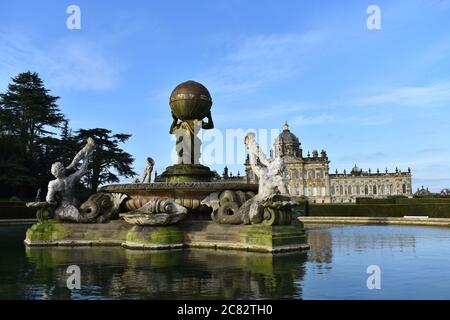 La Fontana dell'Atlante di fronte al fronte Sud del Castello Howard nel Nord Yorkshire, Inghilterra. Riflessioni della casa e fontana in acqua. Foto Stock