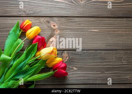 Bouquet di tulipani in una borsa della spesa di carta su sfondo in legno, concetto di sconti e vendite per la festa della donna, la festa della mamma o pasqua Foto Stock