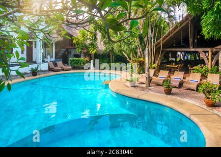 Splendida piscina tropicale con acque turchesi vibranti, circondata da lussureggiante vegetazione tropicale e da edifici resort. Foto Stock