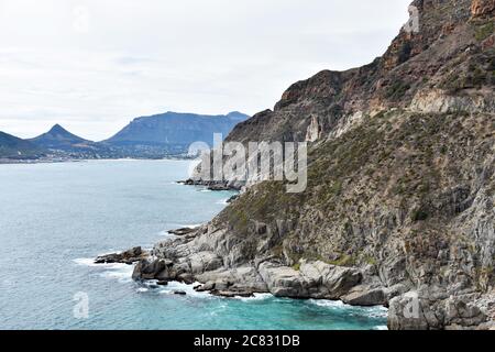 Una vista da Chapmans Peak Drive che guarda verso Hout Bay. L'Oceano Atlantico incontra la scogliera. Capo Peninsular, Sudafrica. Foto Stock