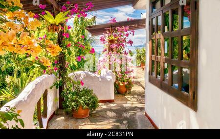 Colorata vista esterna del balcone di un hotel sul mare, con pareti bianche in stile mediterraneo e vivaci fiori di bouganville. Filippine. Foto Stock