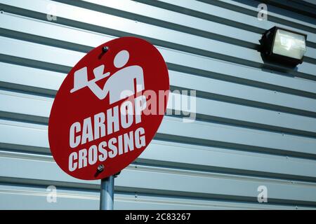 Cartello rosso con l'icona di un server con un vassoio, bevande e cibo fuori da un drive through in un Sonic Drive in un ristorante fast food. Foto Stock