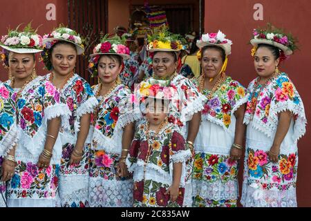 Le donne in hiipil ricamati e cappelli fioriti festive si preparano per la Danza della testa del maiale e del tacchino, o Baile de la cabeza del Foto Stock