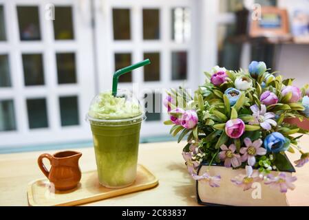 Frullato di tè verde / tè verde Matcha con latte su vetro di plastica sul tavolo in un caffè Foto Stock