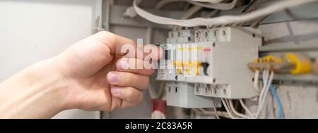 lavoratore professionale di elettricità che risolve il problema di alimentazione di illuminazione domestica, seccando il pannello di alimentazione Foto Stock