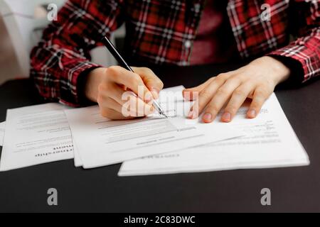 una mano di una persona che tiene una penna e firma il contratto di documento in ufficio, accordo concetto di successo Foto Stock