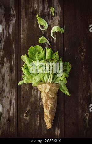 Fresco Lettuce Lleeson in una borsa di carta un tavolo di legno scuro. Insalata di Batavia Foto Stock