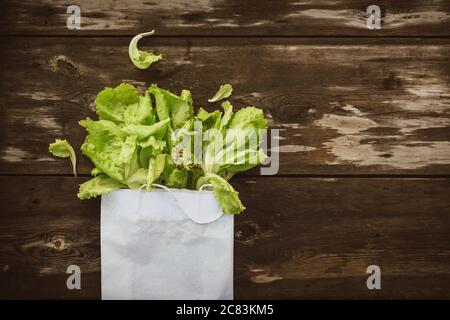 Fresco Lettuce Lleeson in una borsa di carta un tavolo di legno scuro. Insalata di Batavia Foto Stock