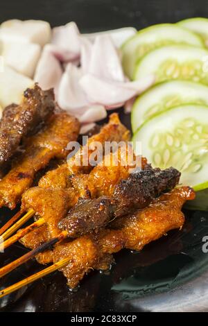 Primo piano verticale del satay di polli e di montone nel presentazione Foto Stock