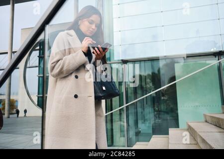 Giovane uomo d'affari in mano con la borsa con sicurezza utilizzando cellulare all'aperto Foto Stock