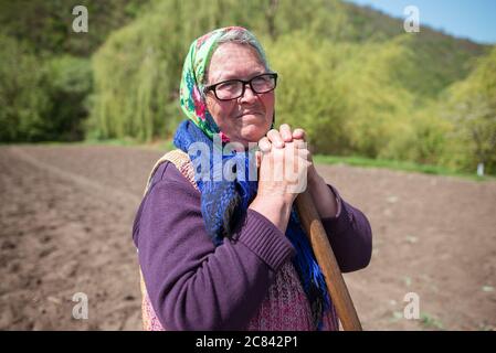 Trebujeni / Moldavia - 15 maggio 2020: Ritratto di donna moldova adulta con caraffa tradizionale che tiene la pala in zona rurale Foto Stock