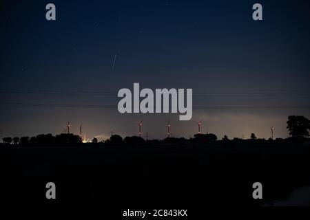 turbine eoliche incandescenti con le loro luci rosse all'orizzonte nella notte buia Foto Stock