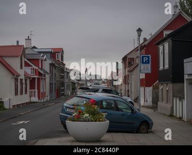 Islanda, Reykjavik, 30 luglio 2019: strada nel centro di Reykjavik con vecchie case storiche in lamiera rossa, chiesa e auto parcheggiate. Foto Stock