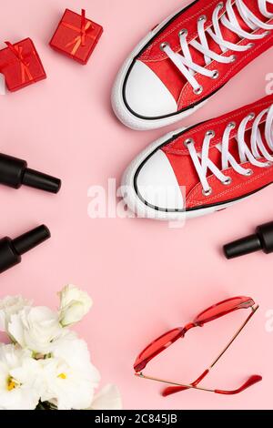 Composizione creativa con sneakers, cosmetici e accessori rossi Foto Stock