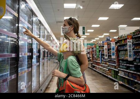 Shopping in famiglia a Morrisons UK supermercato con facemark protettivi per proteggere contro la diffusione di infezione di coronavirus, Londra, Inghilterra Regno Unito Foto Stock