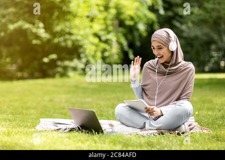 Ragazza eccitata in hijab che ha lezioni in linea, insegnante di allegria Foto Stock