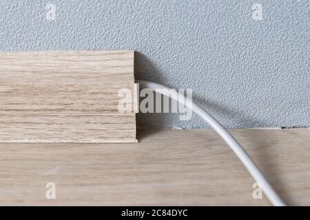 Cavo Internet che si stesa lungo la parete nella baseboard. Riparazione e installazione di attrezzature in casa Foto Stock