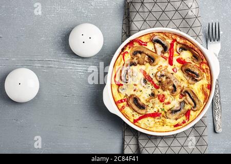 Frittata con funghi e pepe dolce su un tavolo di legno grigio. Foto Stock