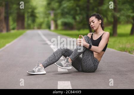 Dolore al ginocchio. Giovane donna sportiva massaggiante dolorosa gamba ferita, sofferente di trauma Foto Stock