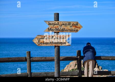 Marocco, Tangeri: Vecchio uomo visto da dietro guardando lo skyline, contro una recinzione di legno vicino al faro di Capo Spartel, promontorio lungo il Foto Stock