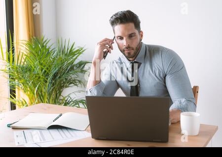 Giovane bussinessman che lavora e beve caffè nel suo ufficio Foto Stock