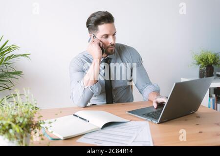 Giovane bussinessman che lavora e beve caffè nel suo ufficio Foto Stock