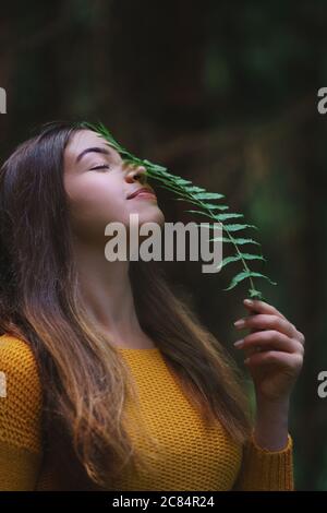 Primo piano ritratto di giovane donna su una passeggiata all'aperto in foresta in natura, tenendo ferno. Foto Stock