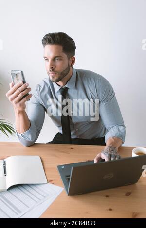 Giovane bussinessman che lavora e beve caffè nel suo ufficio Foto Stock