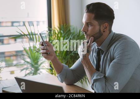 Giovane bussinessman che lavora e beve caffè nel suo ufficio Foto Stock