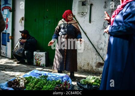 Marocco, Tetouan: Scena dalla vita quotidiana con gli abitanti della medina, registrato come patrimonio dell'umanità dell'UNESCO. Donna anziana velata che vende il vego Foto Stock